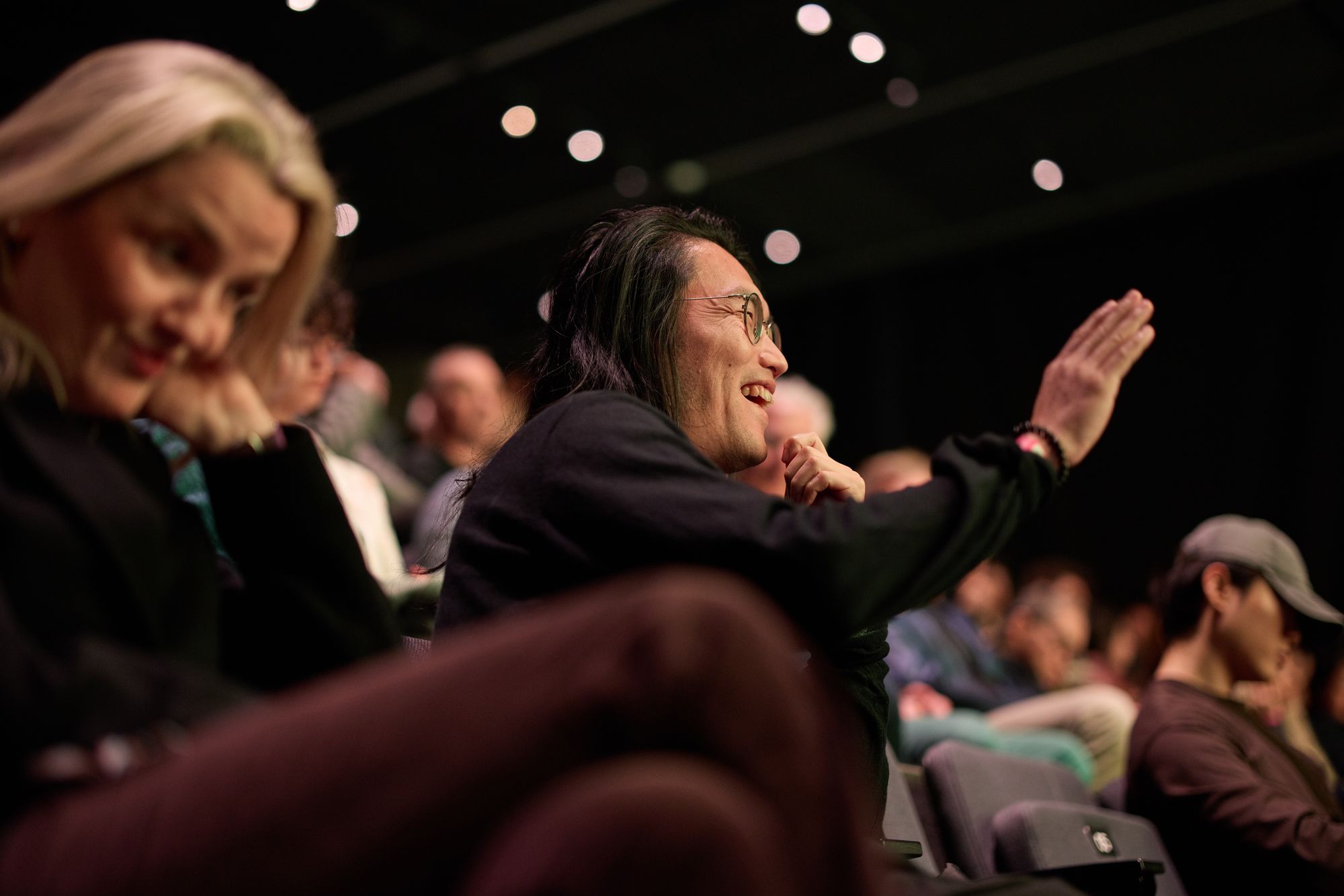 A laughing attendee raises a hand to ask a question.
